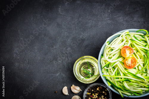 Bowl with raw spiralized zucchini noodles. Top view, space for text.