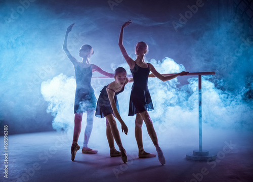 The young ballerinas stretching on the bar photo