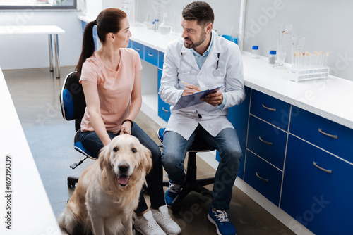 Serious doctor talking to owner of his patient