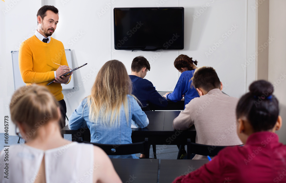 Teacher monitoring students' work during examination test in class Stock  Photo | Adobe Stock