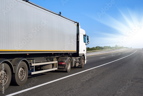 Truck on road with container and bright sun, cargo transportation concept