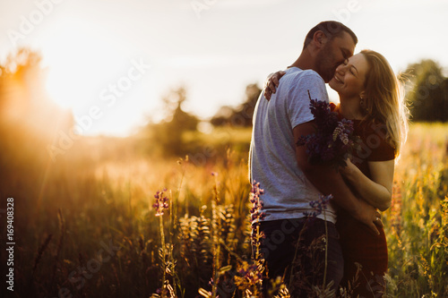 Cheerful couple hugs each other tender standing on the green field