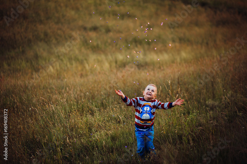 Cheerful child throws petals up posing on the field of lavander