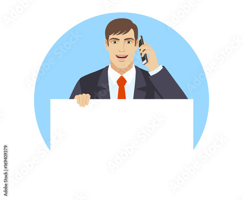 Businessman holding white blank poster and talking on the mobile phone