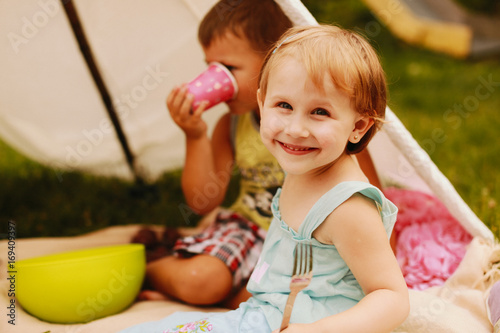 Blonde litle girl holds fork sitting on picnic