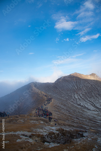 Hundreds of tourists on mountains Kawah Ijen Volcano crater going to see Sulfuric acidic big lake a famous in Indonesia