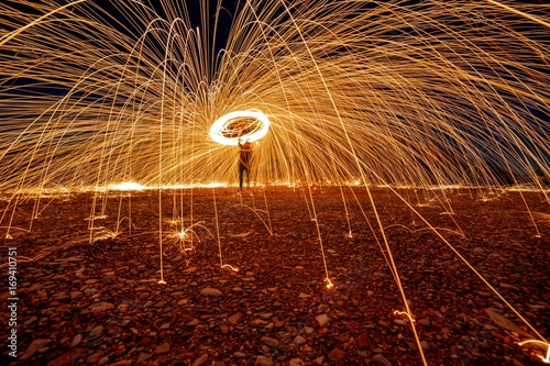 Man spinning illuminated steel wool at night, Italy