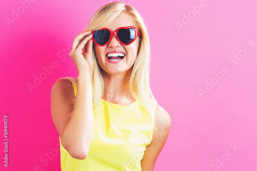 Young woman with sunglasses on a pink background