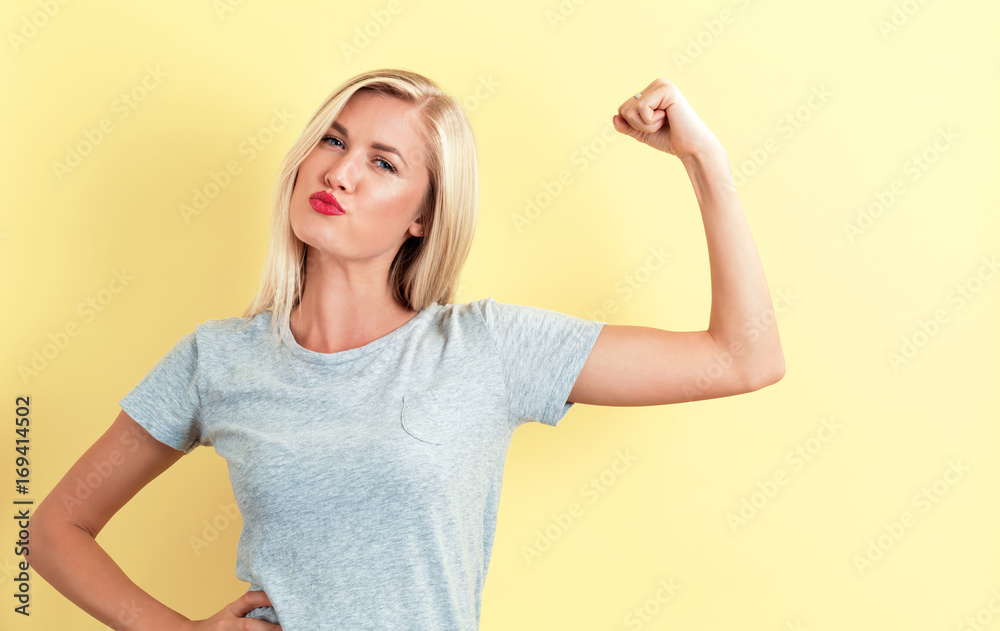 Powerful young woman on a yellow background - obrazy, fototapety, plakaty 