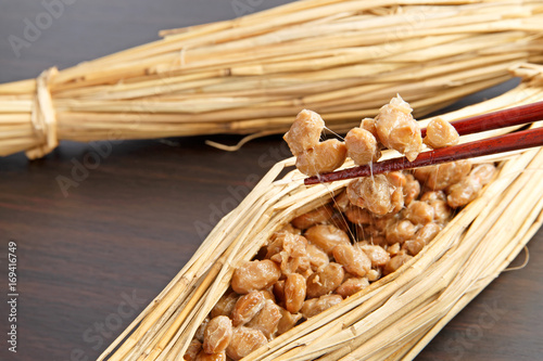 Natto fermented soy beans wrapped in rice straw on wood background