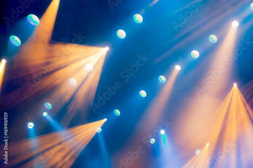 Lighting equipment on the stage of the theatre during the performance. The light rays from the spotlight through the smoke. Blue and yellow rays of light. photo