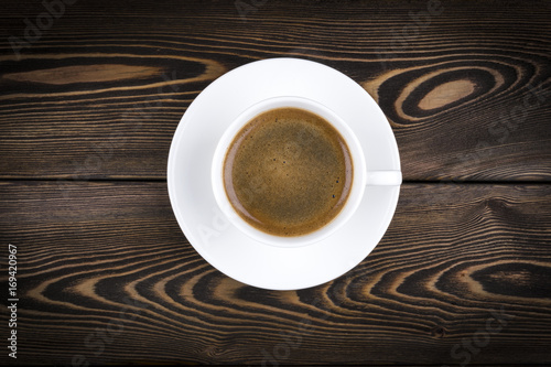 Overhead view of a freshly brewed mug of espresso coffee on rustic wooden background with woodgrain texture. Coffee break style  concept