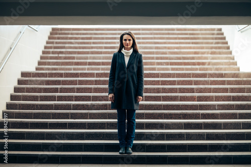Lonely beautiful woman standing on underground stairs