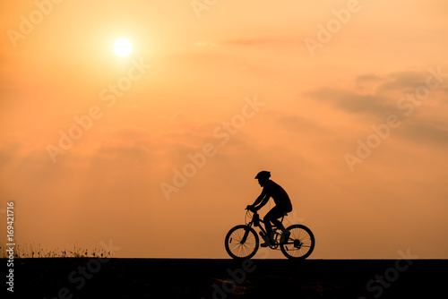 Silhouette of cyclist on sunset background
