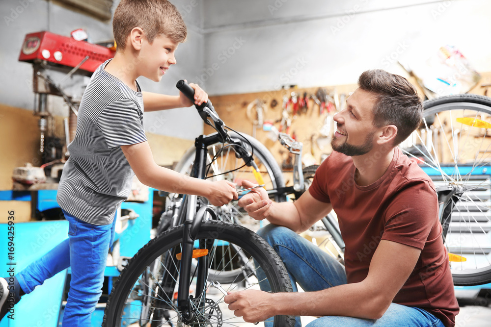 Obraz premium Dad and son fixing bicycles in garage