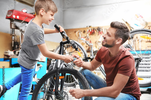 фотографія Dad and son fixing bicycles in garage