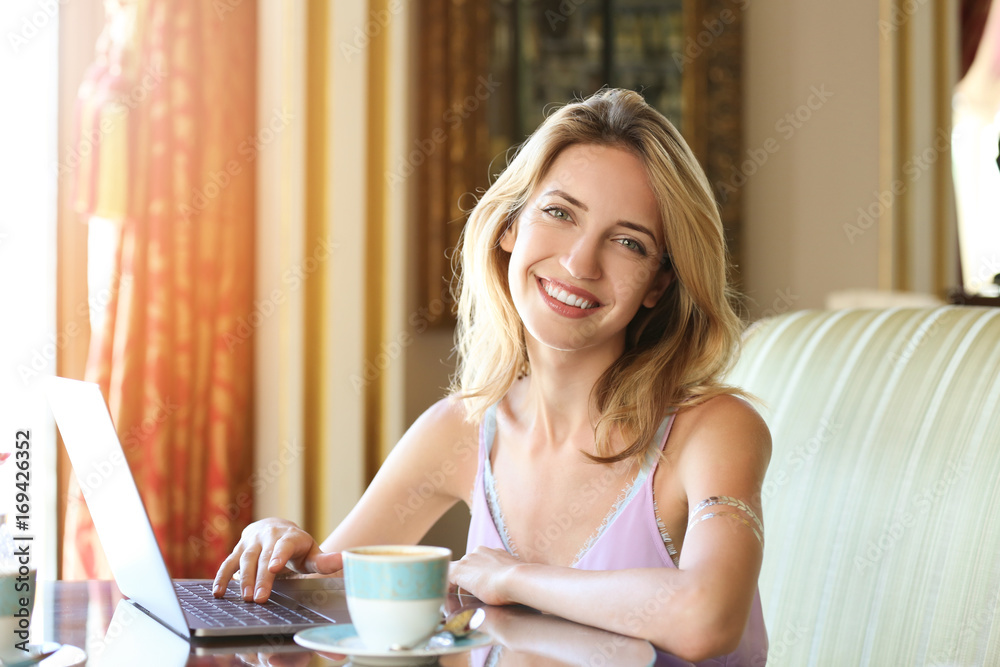 Beautiful young woman working with laptop and drinking coffee in cafe Beautiful young woman working with laptop and drinking coffee in cafe