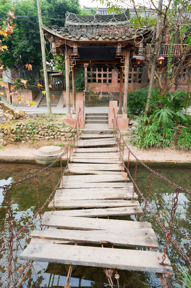 suspension bridge made with wood planks and chains above a river in China suspension bridge made with wood planks and chains above a river in China