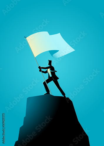 Businessman holding a flag on top of rock