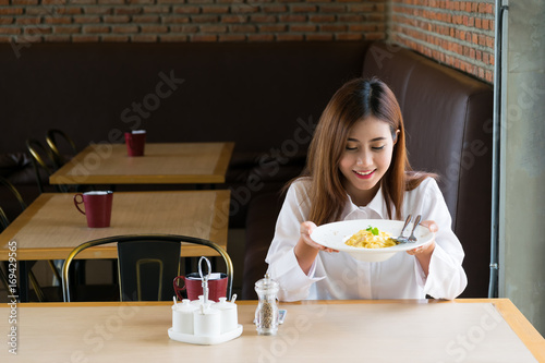 A woman holds a spaghetti in a restaurant.