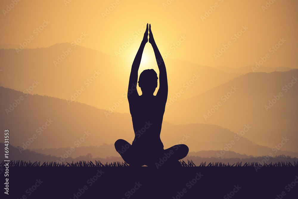 Silhouette young woman practicing yoga on the muontain at sunset.Vintage color