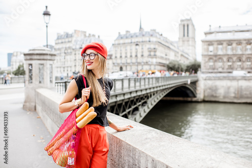 Photography Young stylish woman in red cap walking with mesh bag full of french food on the