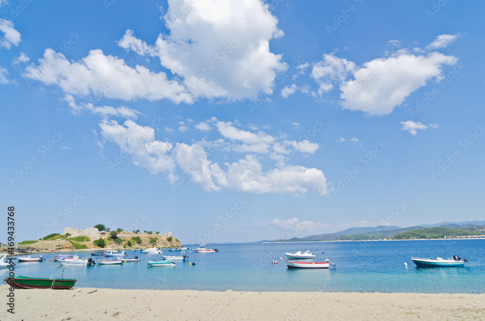 Under the perfect clouds, boats in a small fishing harbour at the beach in Sithonia, Greece