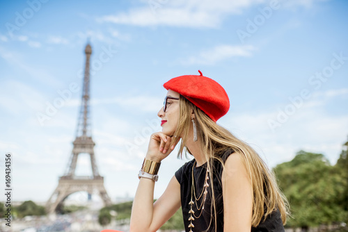 Photography Portrait of a young happy woman in red cap in front of the Eiffel tower in Paris