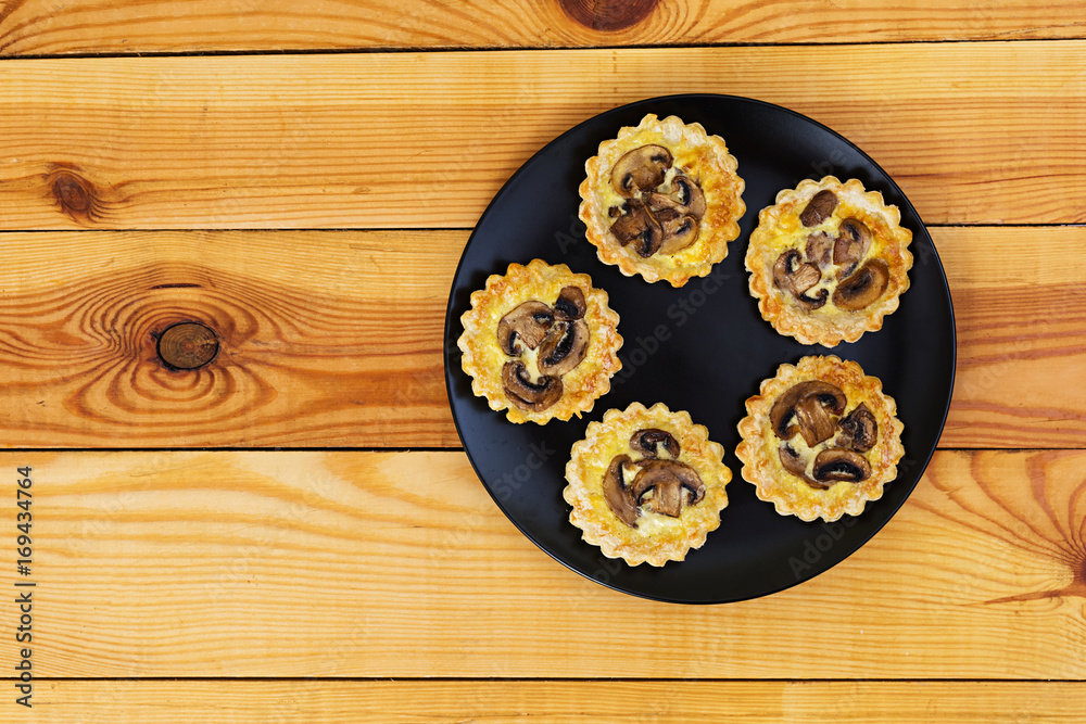 Tartlets with champignons on wooden background Tartlets with champignons on wooden background