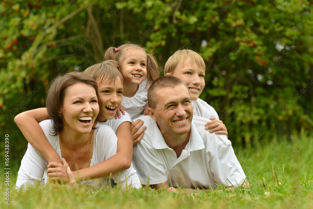 smiling family lying on green grass smiling family lying on green grass