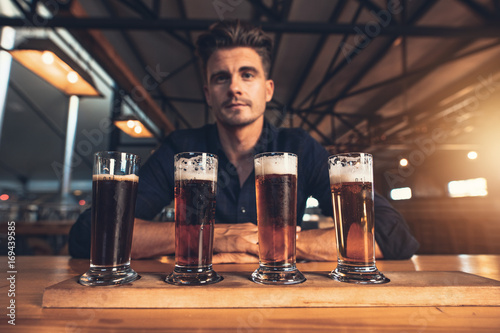 Fotografie Young man tasting different varieties of craft beer
