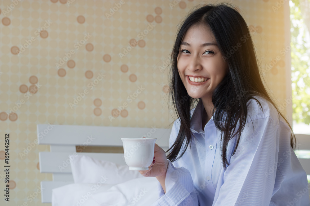 Happy Asian woman drinking coffee on bed Happy Asian woman drinking coffee on bed