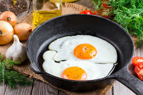 Fried eggs in a frying pan for breakfast on a black background