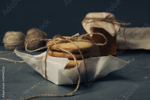 Homemade sugar cookies with honey. Ginger breads with bakey paper tied with a rope on grey background photo