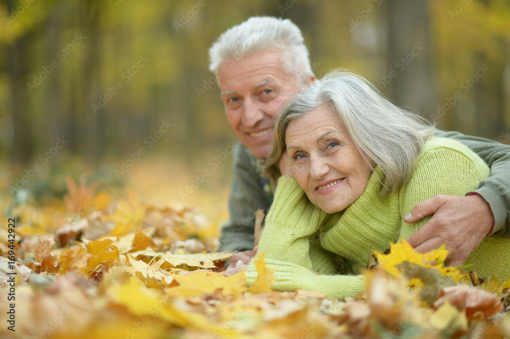 Elderly couple lying on autumnal leaves Elderly couple lying on autumnal leaves