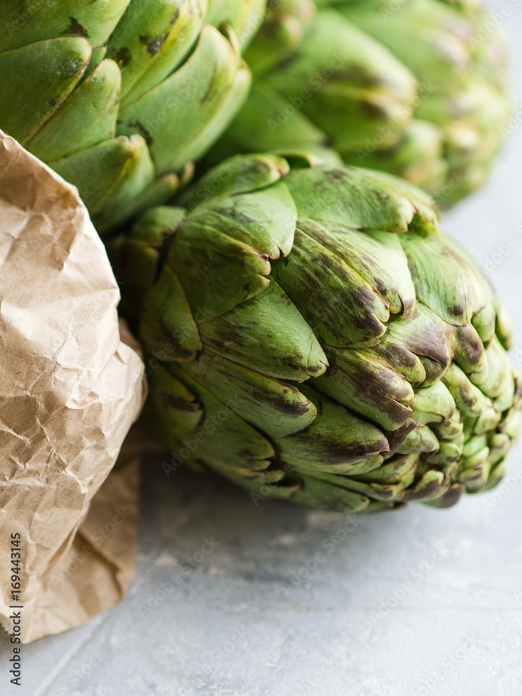 Fototapeta premium Ripe artichokes in a paper bag on a gray background