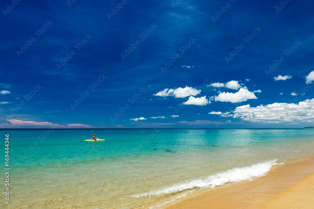 Naklejka premium Lifesaver sitting on surfboard in water at Mai khao beach, Phuket island, Thailand.