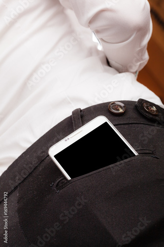 Mobile phone in rear trousers pocket. © Voyagerix