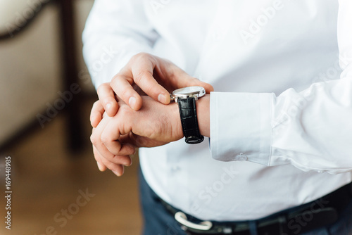 Fat groom clasping stylish watch band on his wrist