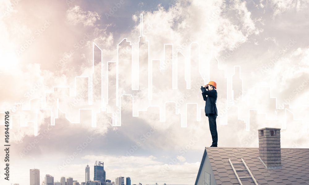 Engineer man standing on roof and looking in binoculars. Mixed m Engineer man standing on roof and looking in binoculars. Mixed m