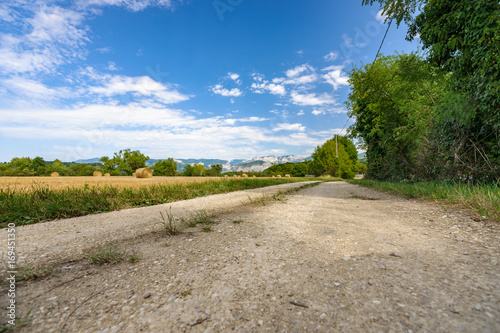 Farmland road in a mountain landscape with fields filled with hay bales