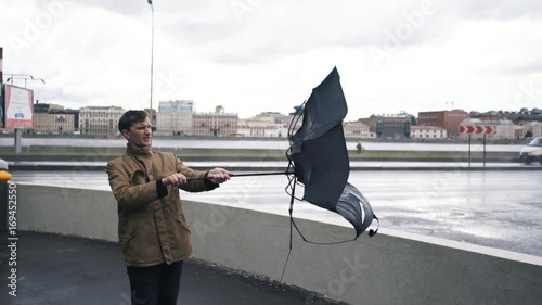 Man in jacket with umbrella standing outdoors. The gust of wind pulls umbrella out of hand