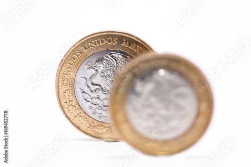monedas mexicanas de 10 y 20 pesos sobre fondo blanco, enfocando la moneda de atras