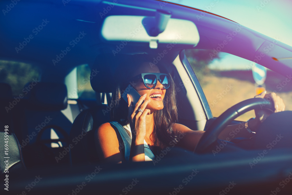 Naklejka premium Young modern woman talking on the phone in the car
