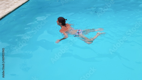 Portrait of beautiful tanned woman in swimwear relaxing in swimming pool