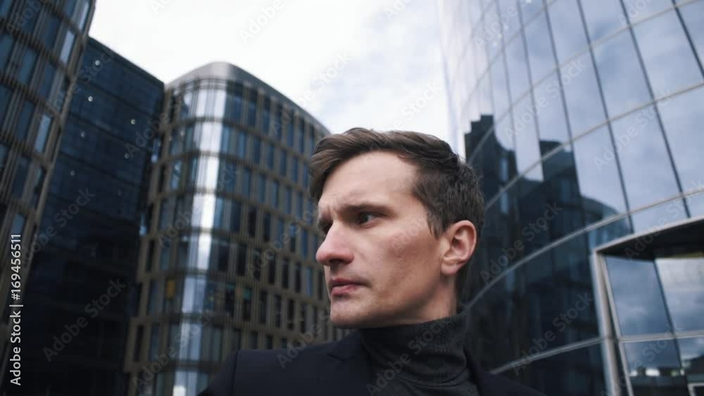 Portrait of young businessman in suit. Glass business centre building at the background Portrait of young businessman in suit. Glass business centre building at the background
