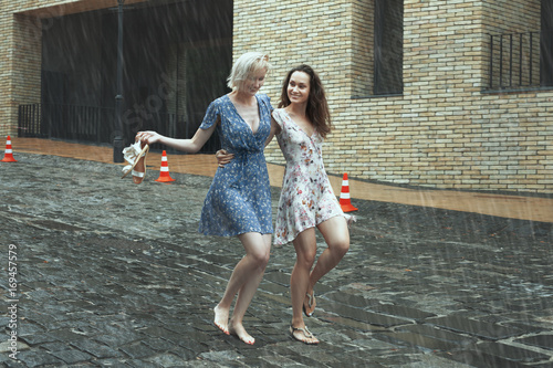 Women are walking in the rain in the city, they are smiling and happy.