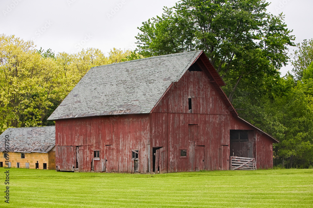 Weathered red barn Green field Trees