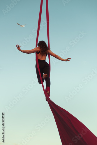 Woman acrobat high in the sky shows tricks.