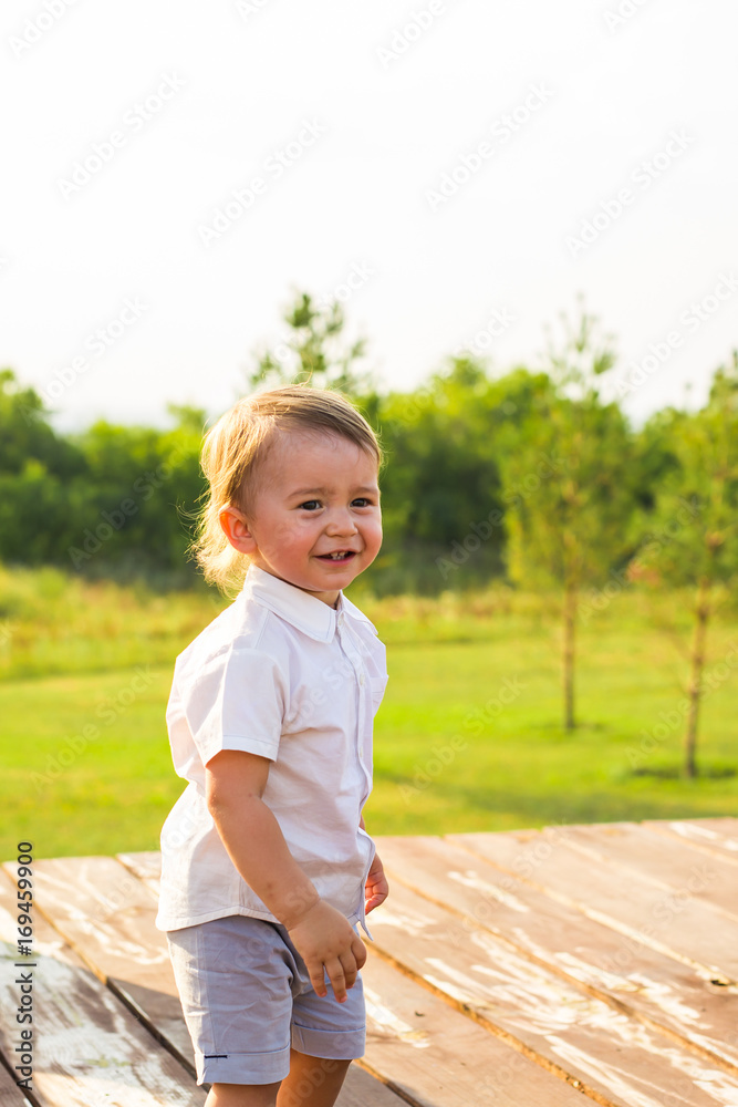 Portrait of cute little baby boy having fun outside. Smiling happy child playing outdoors Portrait of cute little baby boy having fun outside. Smiling happy child playing outdoors